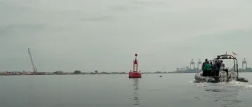 Boat approaching solar powered buoy used by cargo ships for navigation purposes