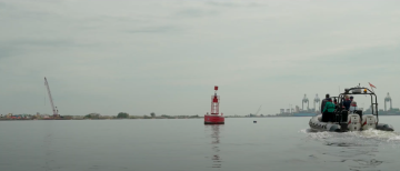 Boat approaching solar powered buoy used by cargo ships for navigation purposes