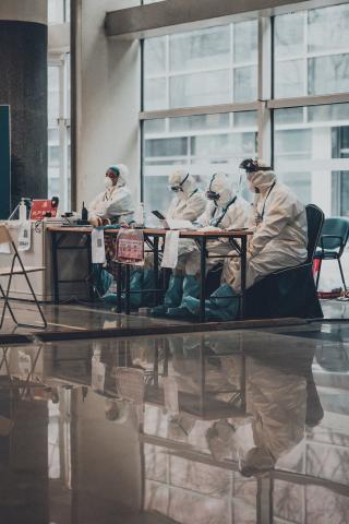 Photo of individuals in protective suits by Tedward Quinn on Unsplash