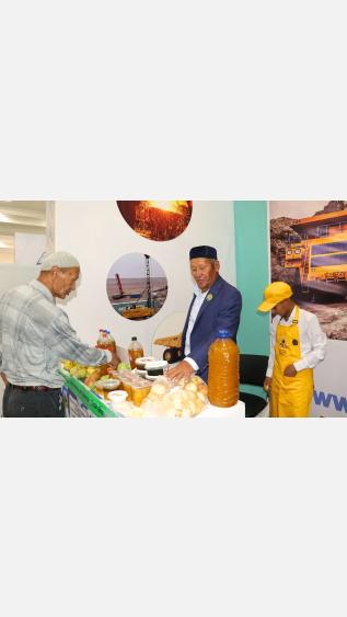 Three men on a fair booth, demostrating honey and fruits of their own production